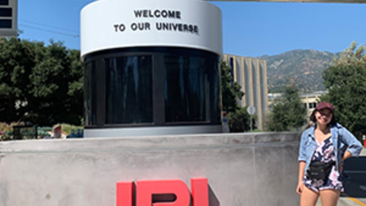 Adrienne stands outside next to the JPL welcome sign.