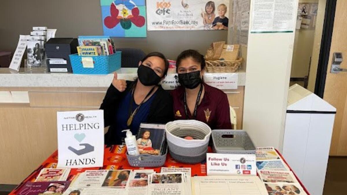 Two women seated behind a table at a health clinic.