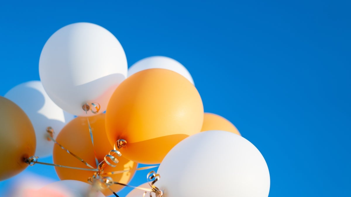 Gold and white balloons against a blue sky.