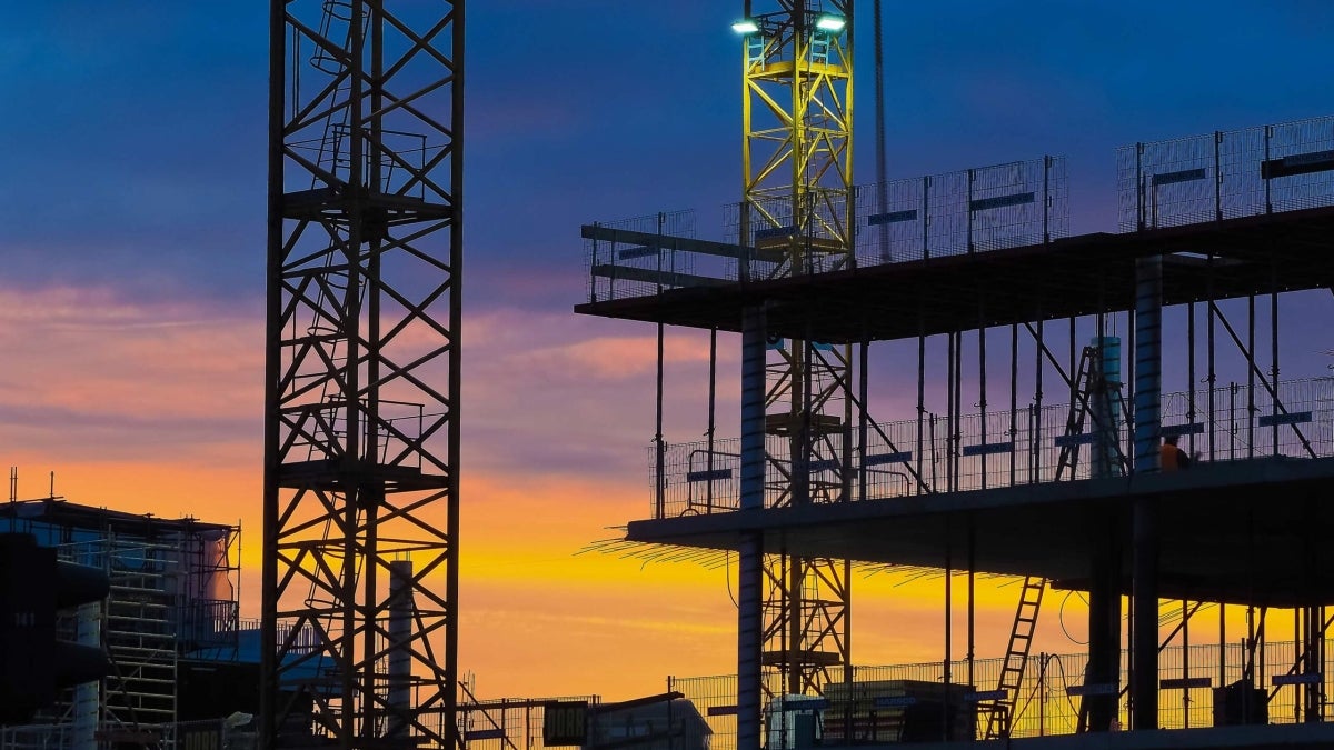 Construction site silhouetted against a sunset.