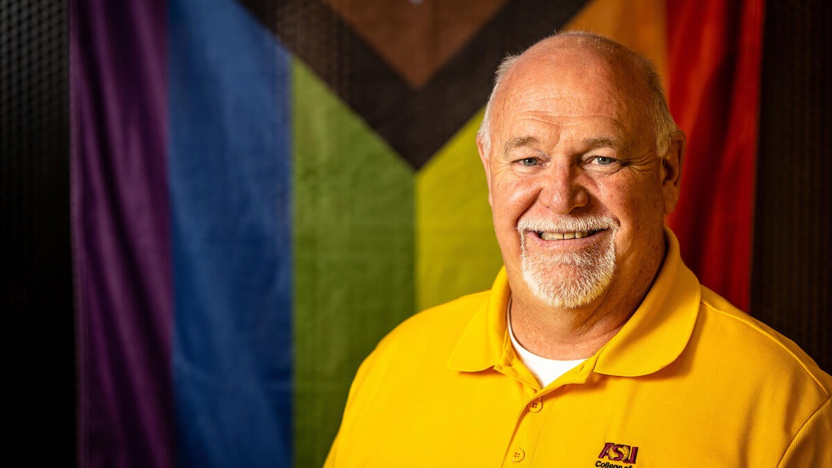 Man's portrait in front of an LGBTQ flag