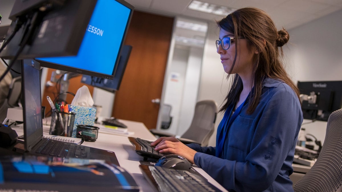 An intern works at a computer in an office.