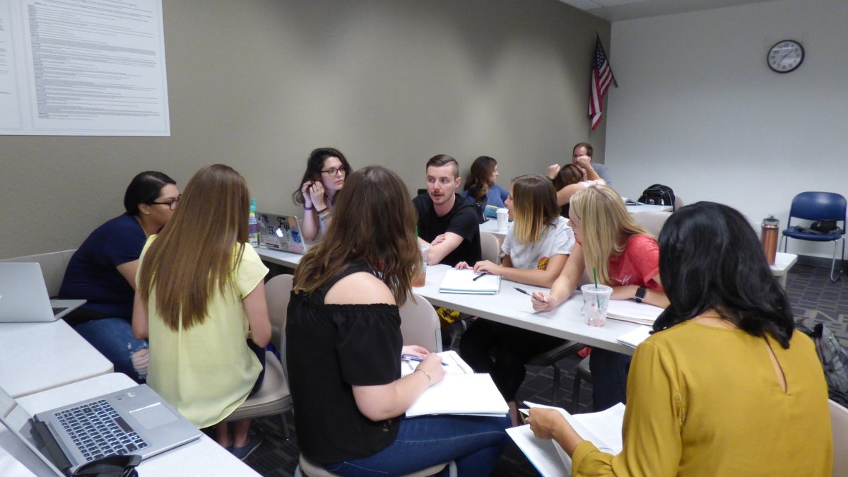 Picture of students around a table discussing a class topic