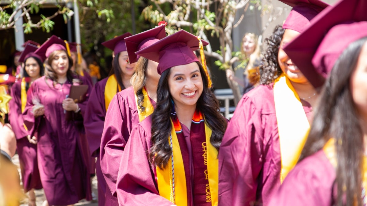 A line of graduates exits their convocation ceremony wearing their caps and gowns