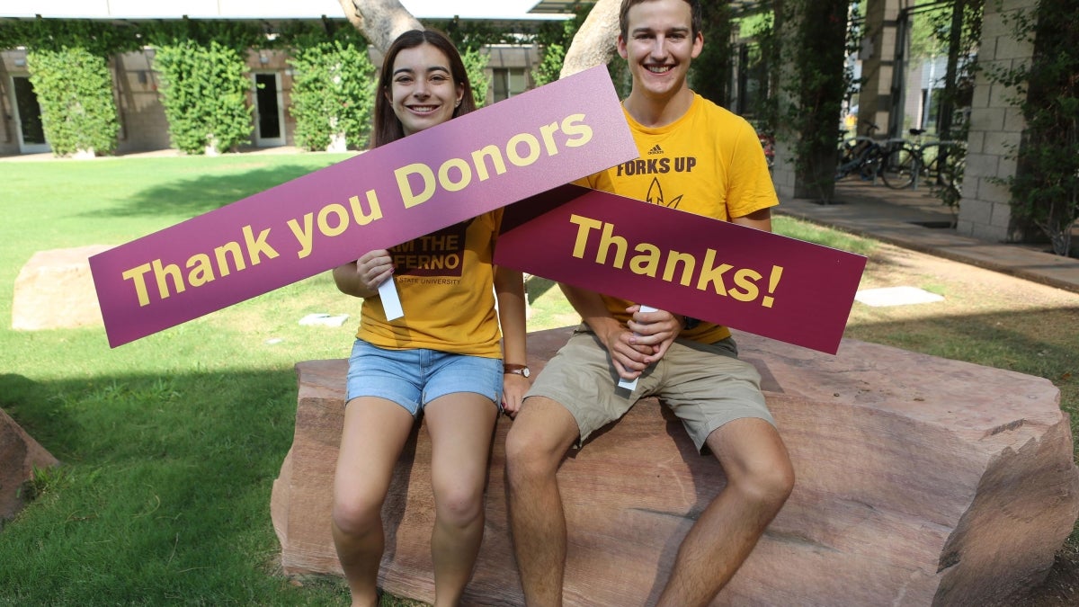 students holding signs that say "Thank you Donors" and "Thanks!"