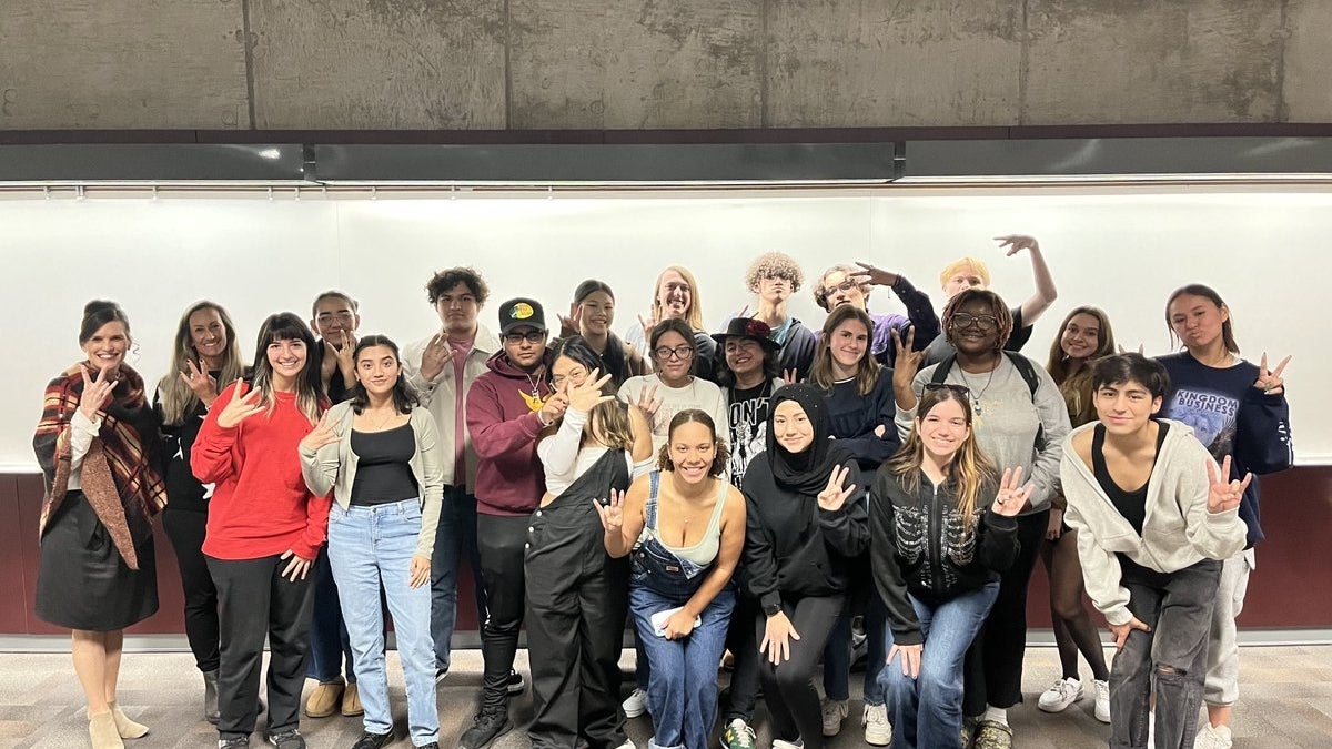 Group of ASU students posing for a photo and making the pitchfork symbol with their hands.