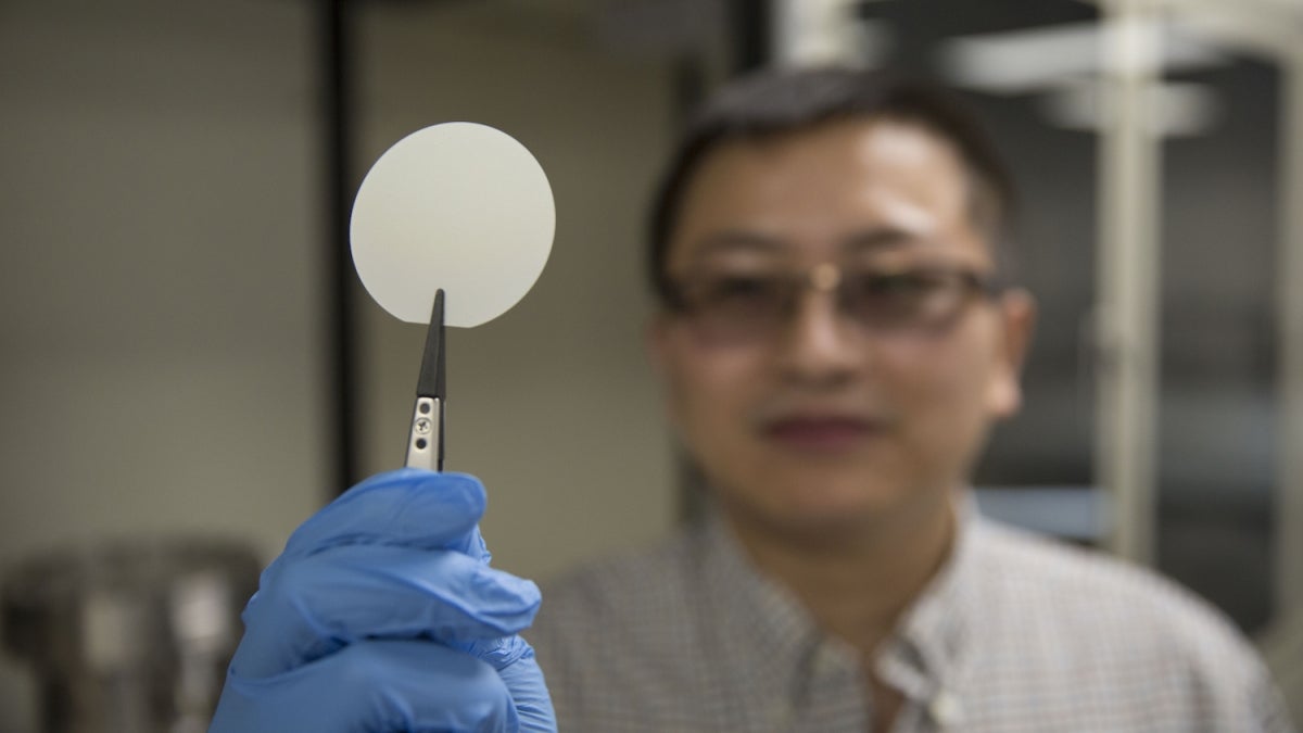 Yuji Zhao holds up a gallium nitride wafer