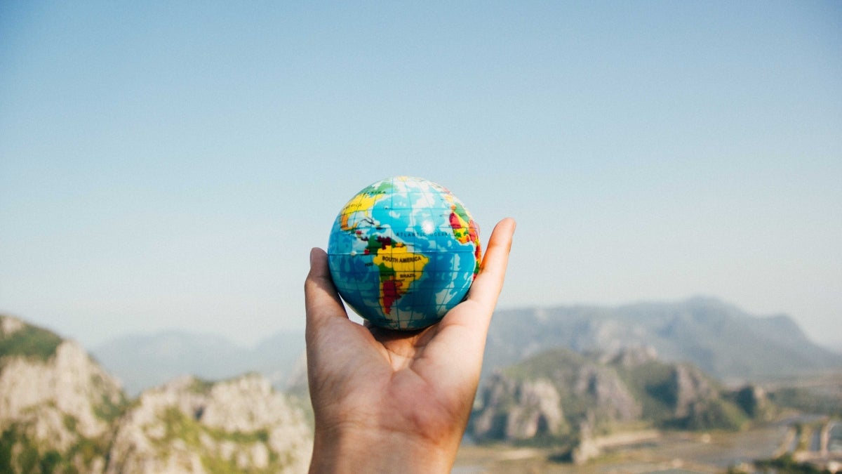 Person's hand holding a small globe