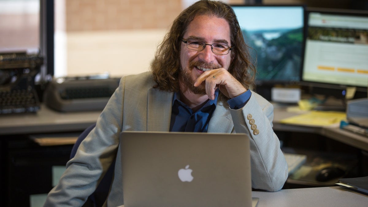 ASU professor Greg Wise sits at a laptop in his office