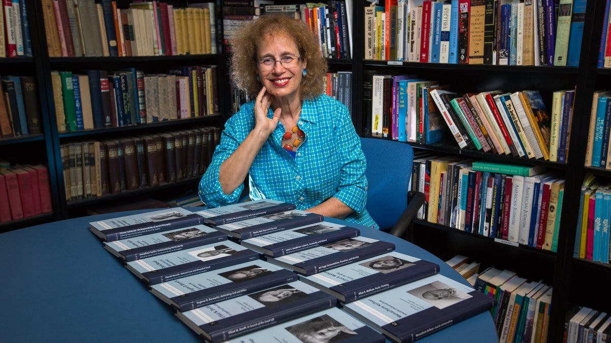 woman sitting in office with volume of books on table