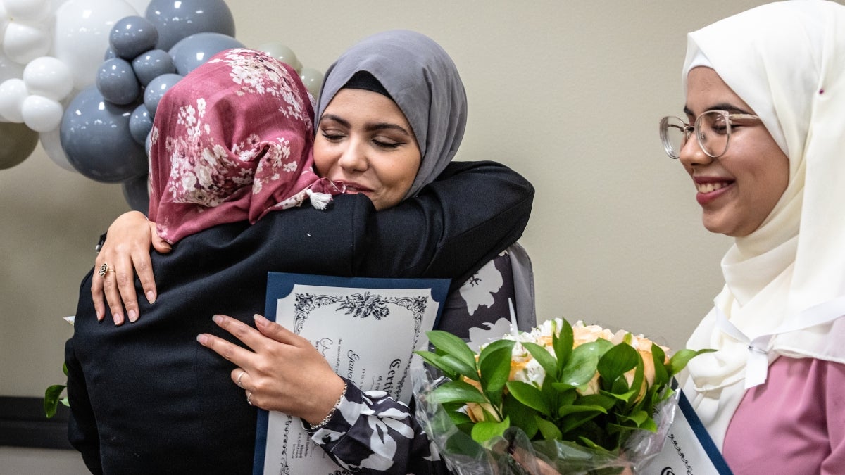 Group of nursing students holding graduation certificates and hugging.