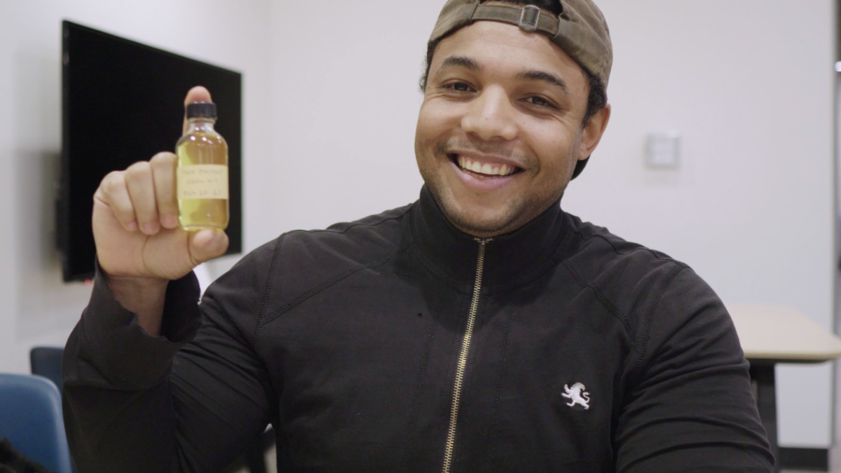 ASU College of Integrative Sciences and Arts alumnus Jordan Collins holds up a small jar of okra-seed oil.