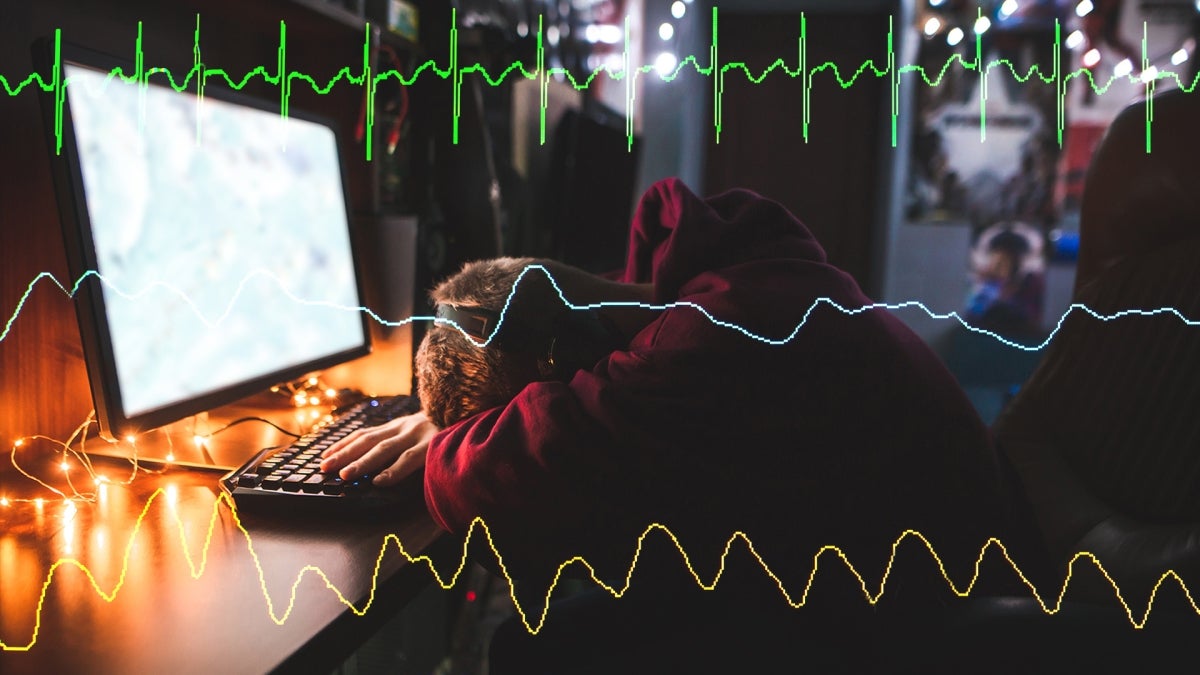 Gamer with head down in front of desktop overlaid with heart monitor line graphs