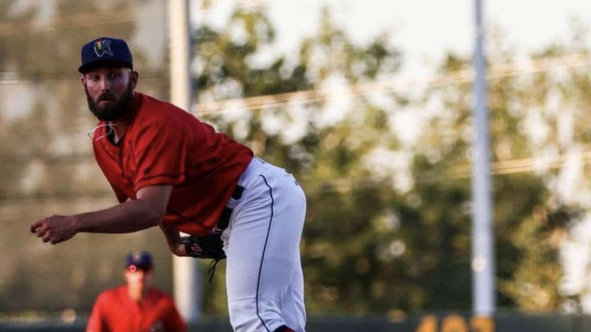 Professional baseball player Zach Featherstone pitches the ball at a Minor League game.