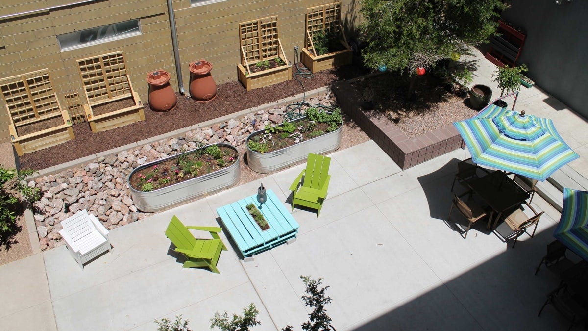 courtyard with colorful umbrellas, chairs, a table and planters