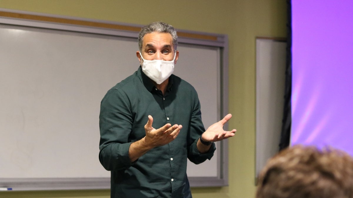 Man wearing a face covering standing at the front of a classroom.