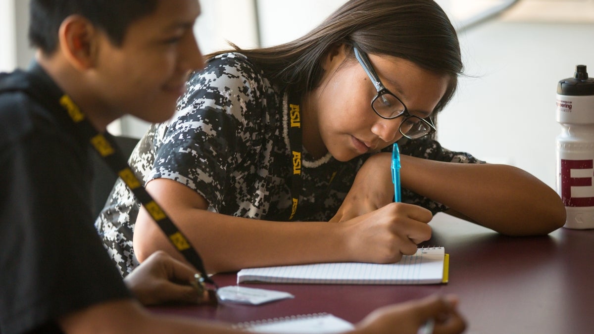 girl writing on paper on a desk