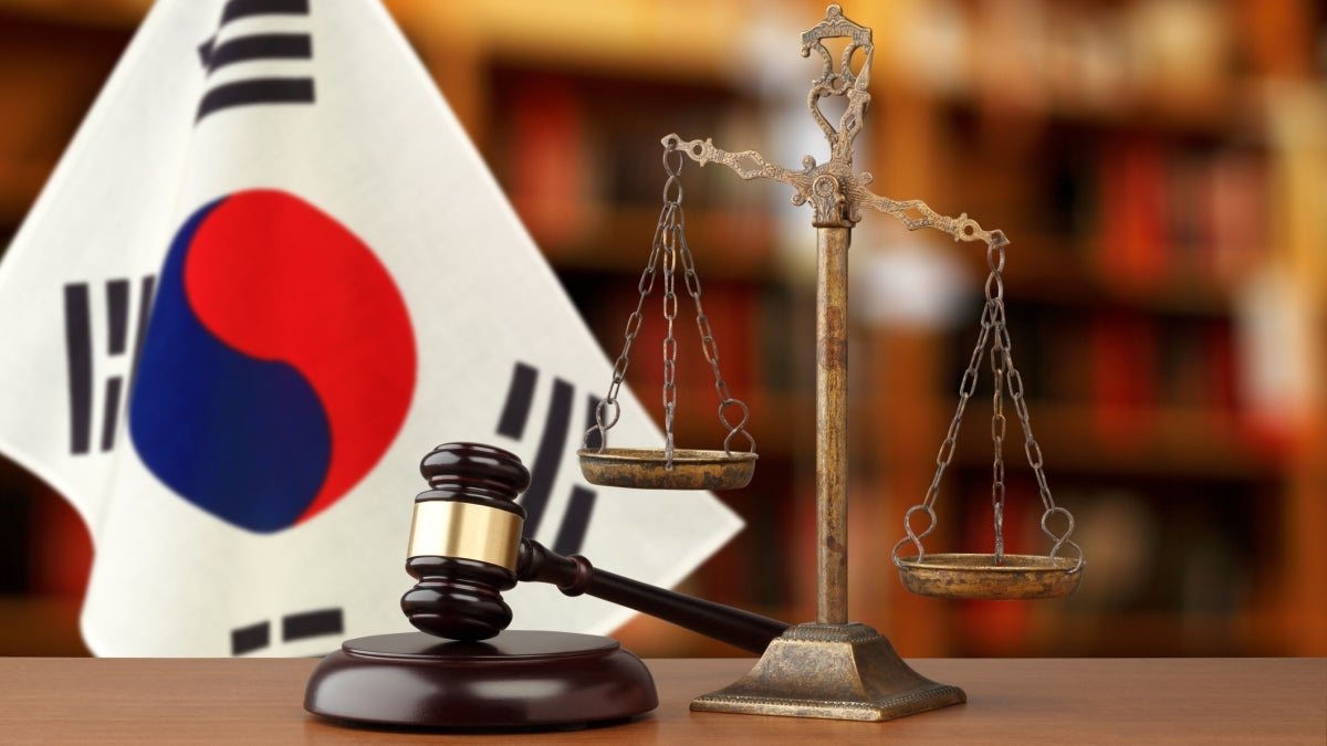 Gavel and justice scales in front of Korean flag.