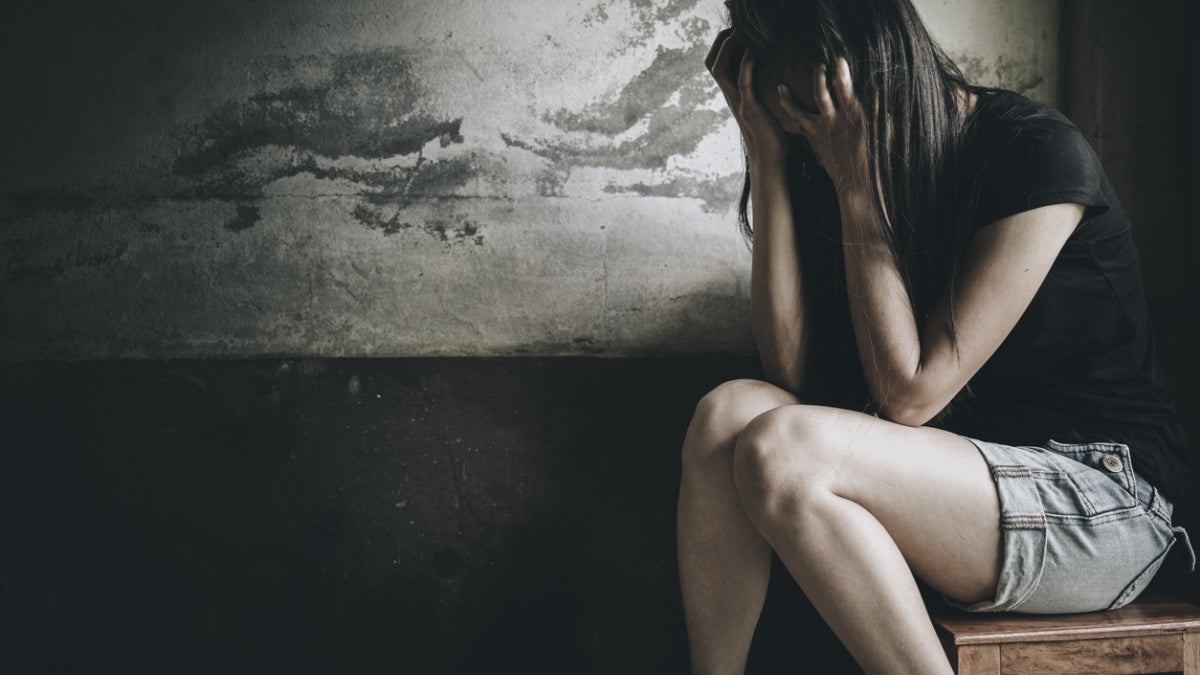 Woman sits on a bench with her heads in her hands.