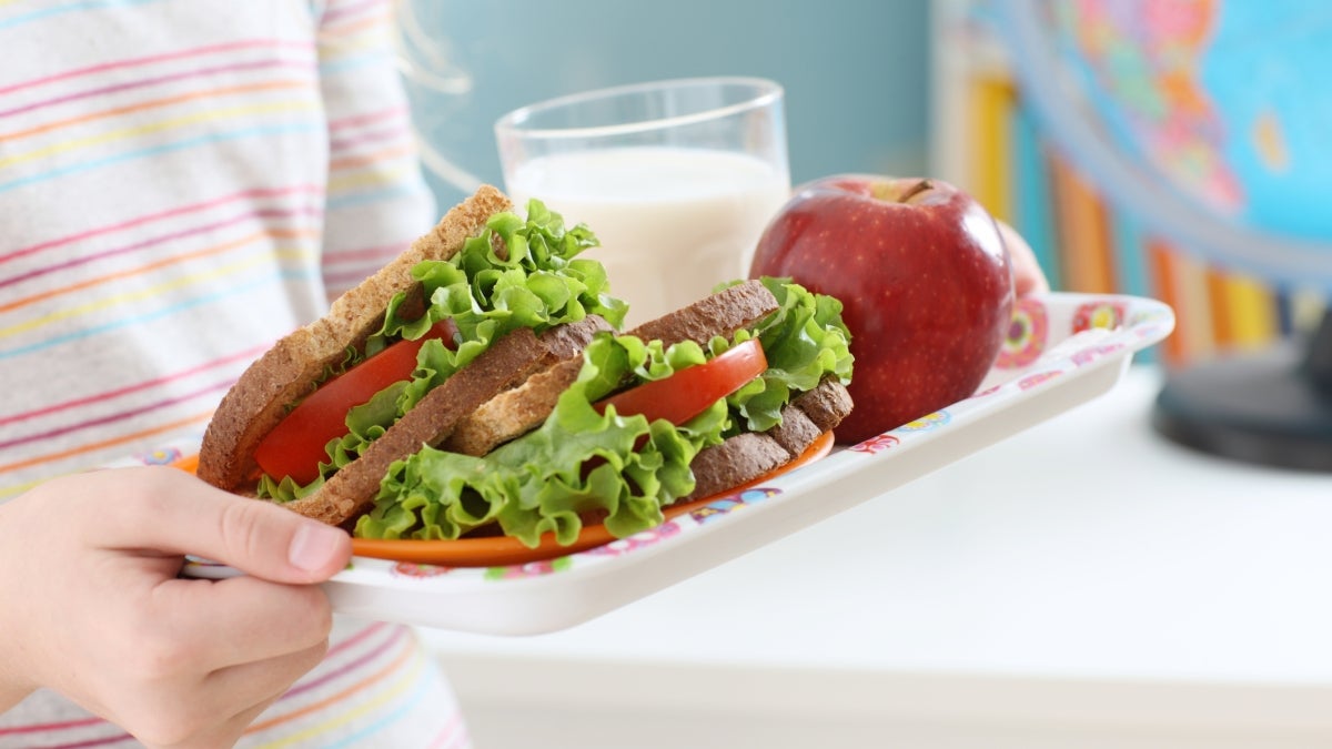 Young student carrying lunch tray of food