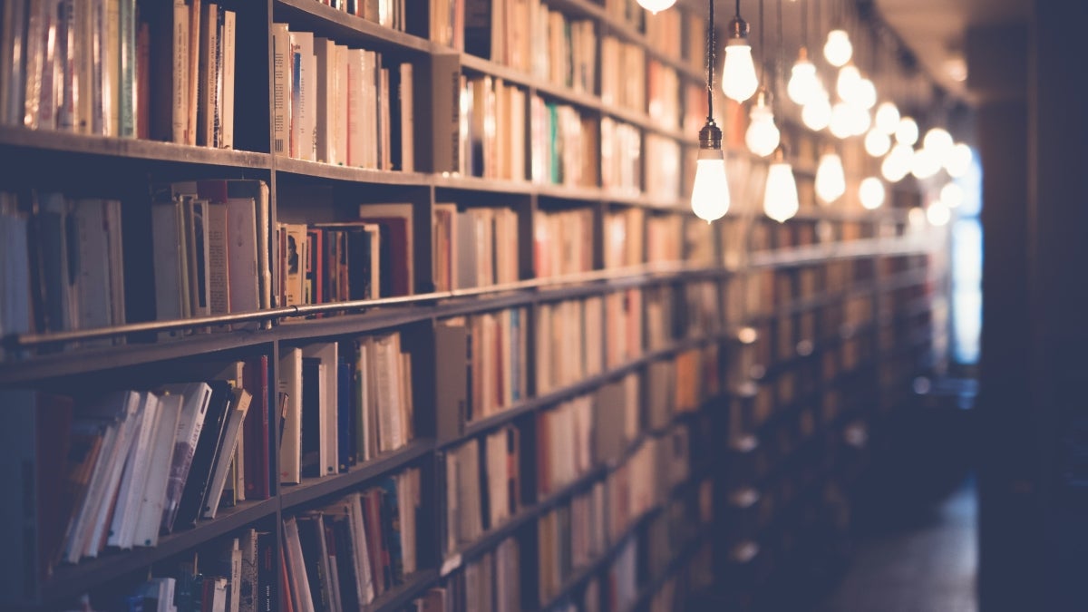 Row of book shelves illuminated by hanging lights.