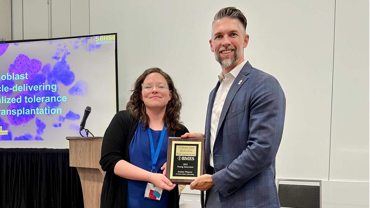 Woman holding an award and standing next to a man.