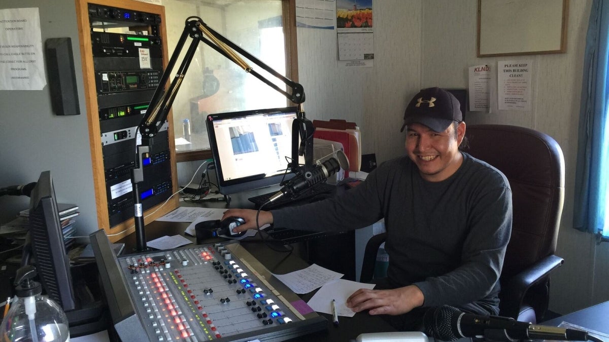 A man sits at a radio control desk