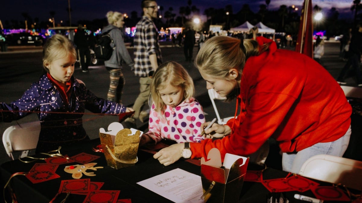 student helps children at event