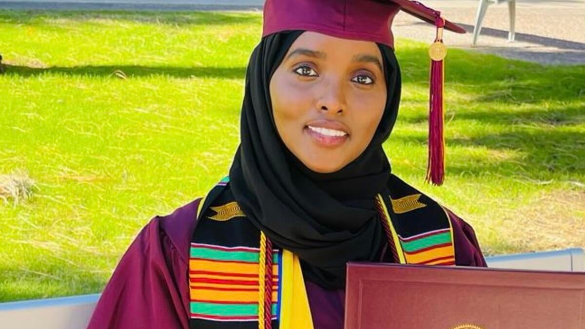 ASU student Maryam Abdulle poses for a photo in a graduation gown and cap, holding her diploma cover