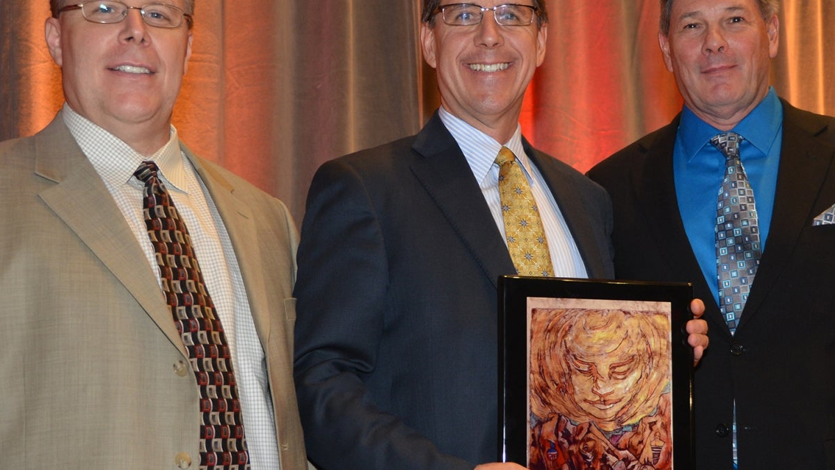 three men posing with award