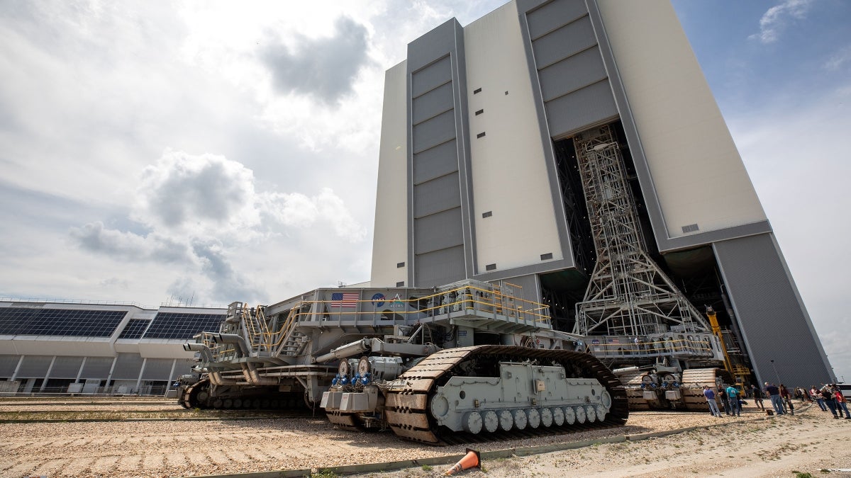 A NASA transporter sits outside a large building.