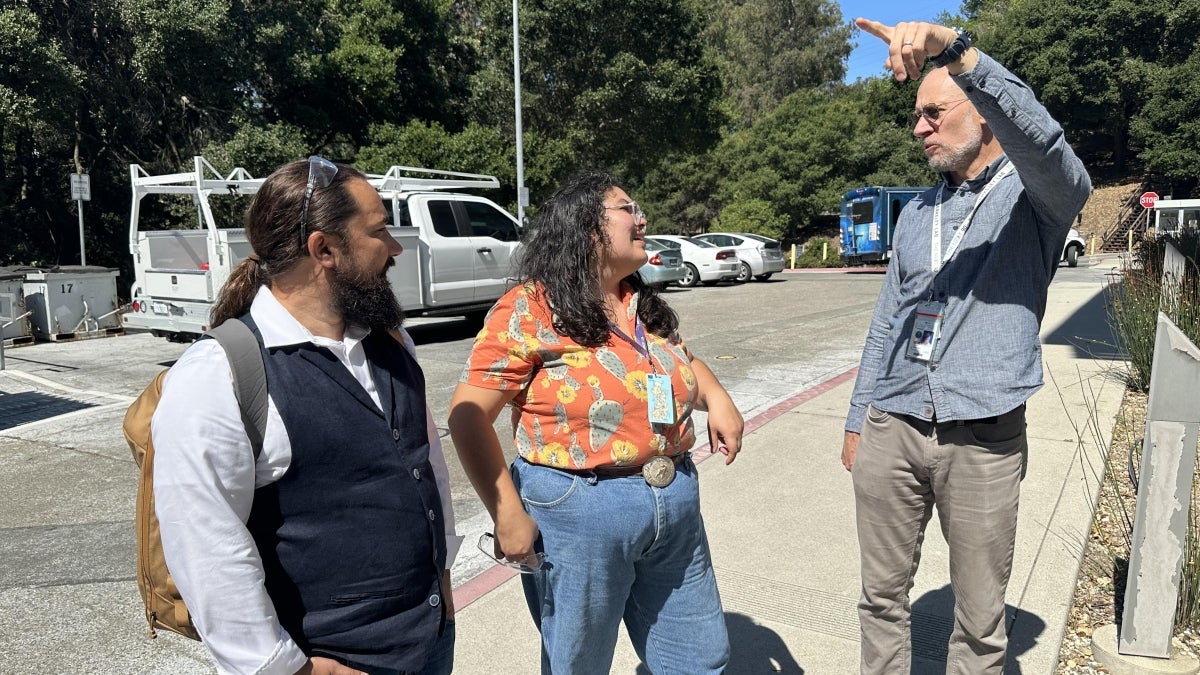 Man pointing while speaking to two other people.