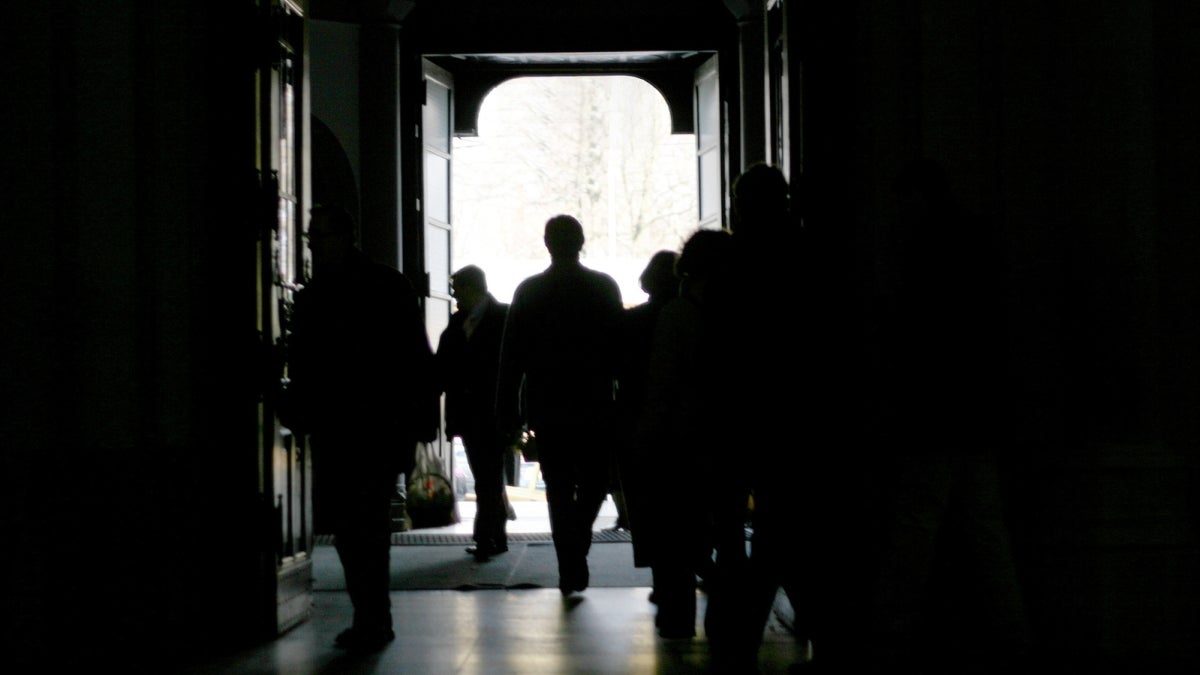 Silhouettes of people walking down a hallway.