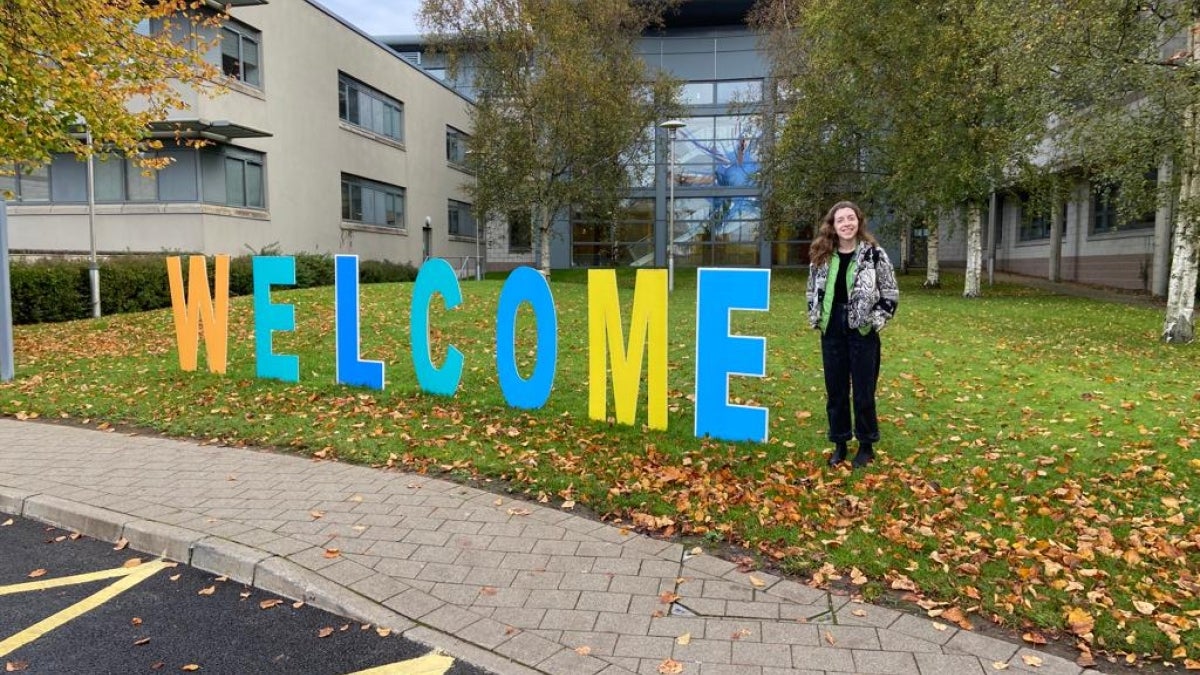 ASU professor standing next to large letters that spell "welcome" on a lawn.