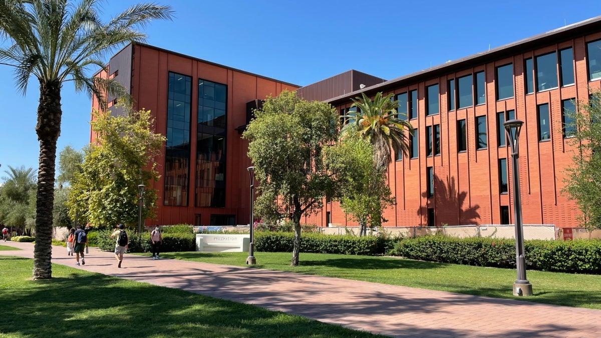 Exterior shot of a brick and glass building surrounded by trees and grass