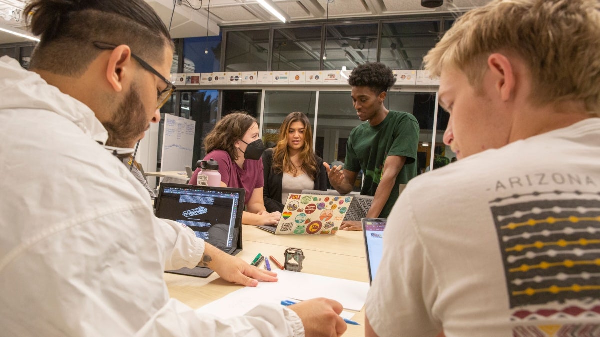 ASU students and members of Solar Devils meeting around a conference table, discussing ideas.