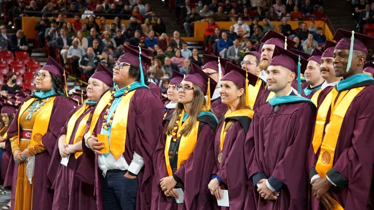 Graduates of ASU's Watts College of Public Service and Community Solutions wear graduation regalia and stand at their graduation ceremony.