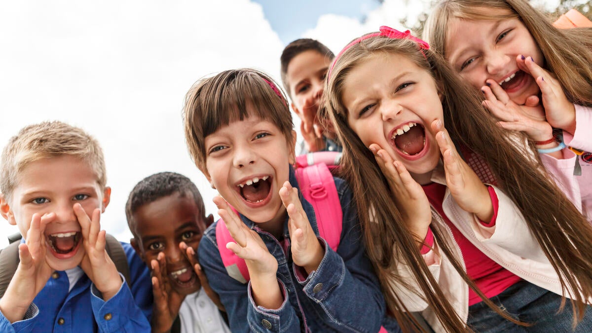 Group of children smiling and shouting at the camera.