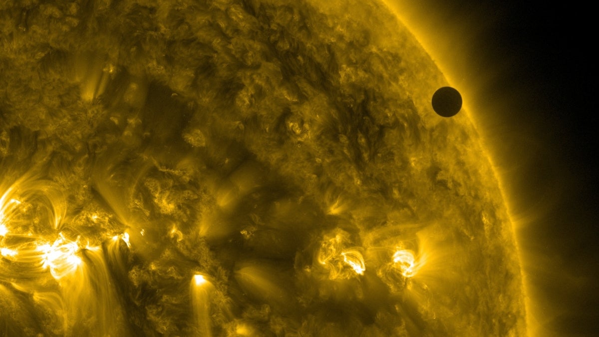 A close up of the sun as the planet Venus appears as a small black dot in front of the sun