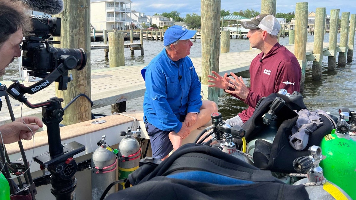 Two people talking on boat being filmed for TV show