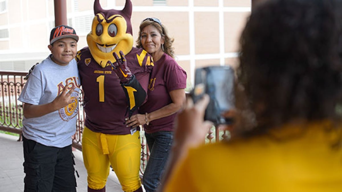 family getting picture taken with ASU mascot, Sparky