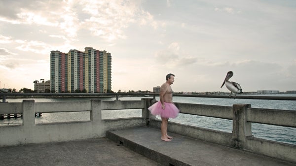 photographer and ASU alum Bob Carey in a tutu on a pier with a bird