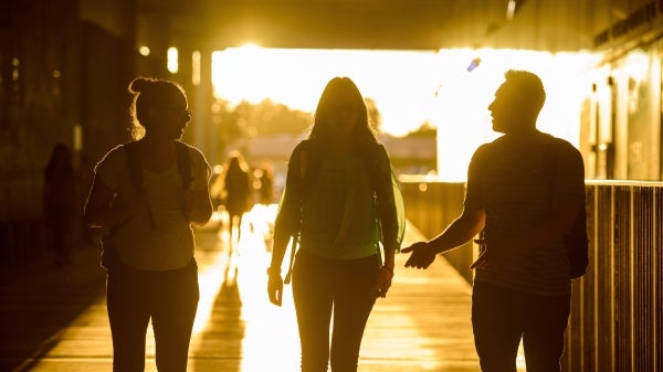 students walking at Coor Hall at sunset