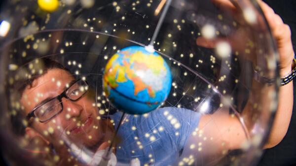 Person wearing glasses looking at a small globe.