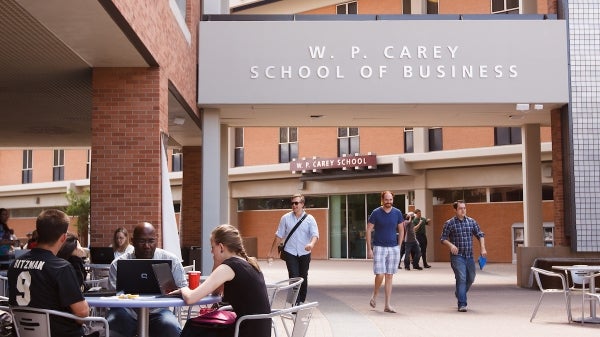 students and professors sit and walk around the exterior of the W. P. Carey School of Business building on ASU's Tempe campus