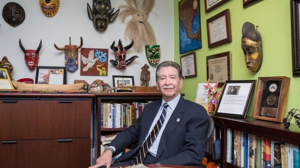 portrait of a man in an office decorated with ethnic masks and books