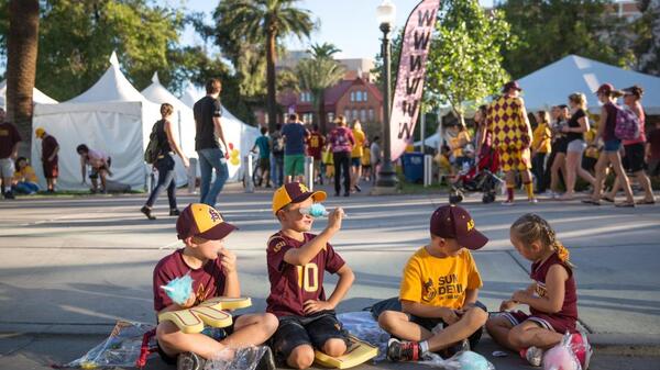 children sitting on sidewalk during parade