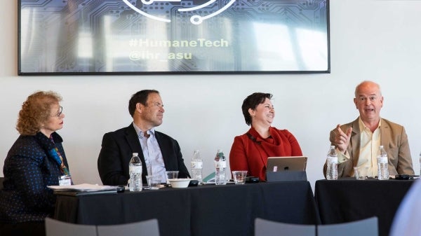 People speaking at a panel sit at tables