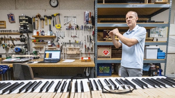 Man gesturing in piano workshop with piano keys laid out in front of him.