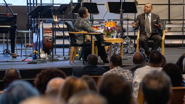 Woman and man sitting and talking on stage during lecture event.